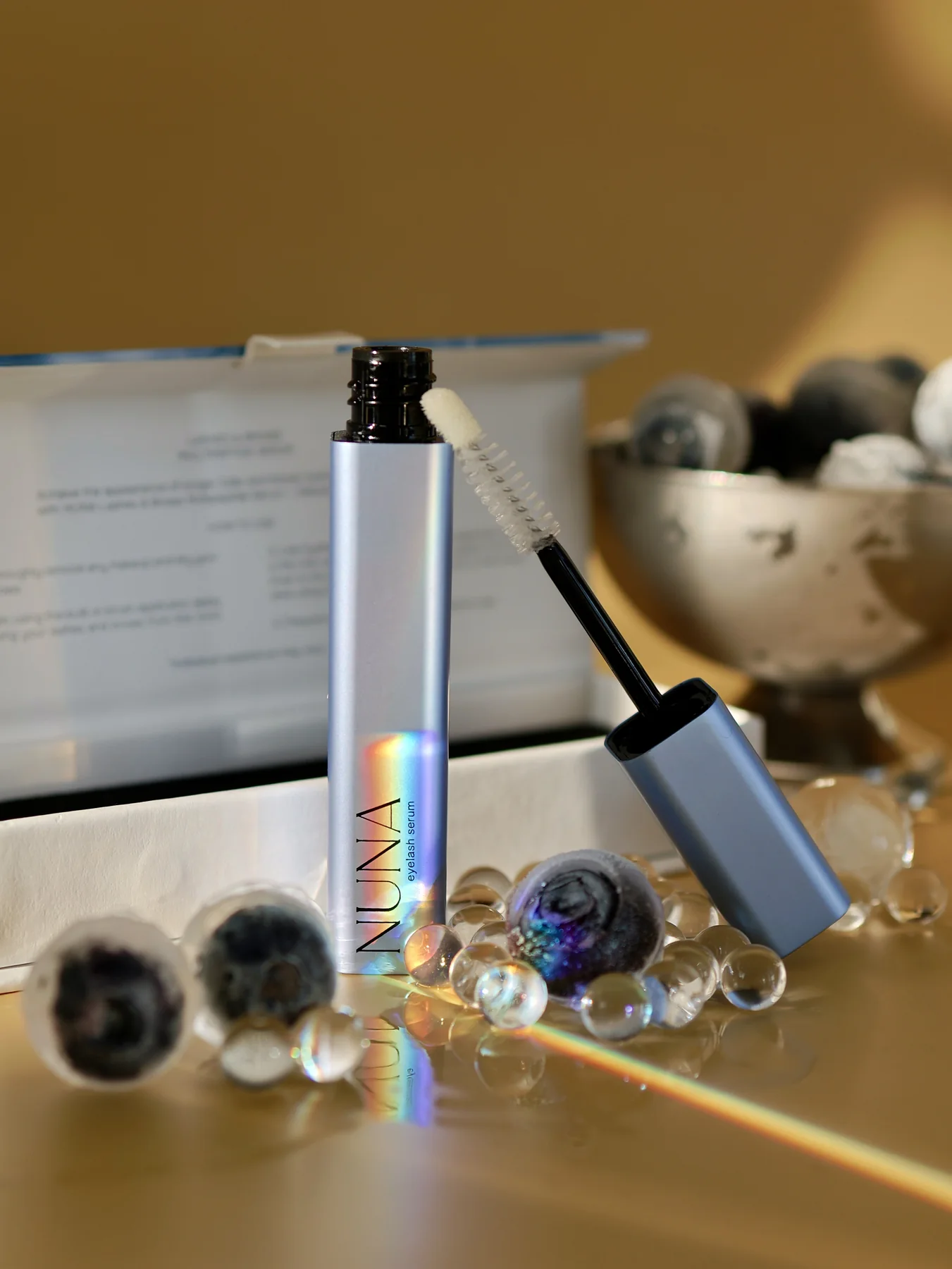 Mascara tube and wand styled with reflective beauty props